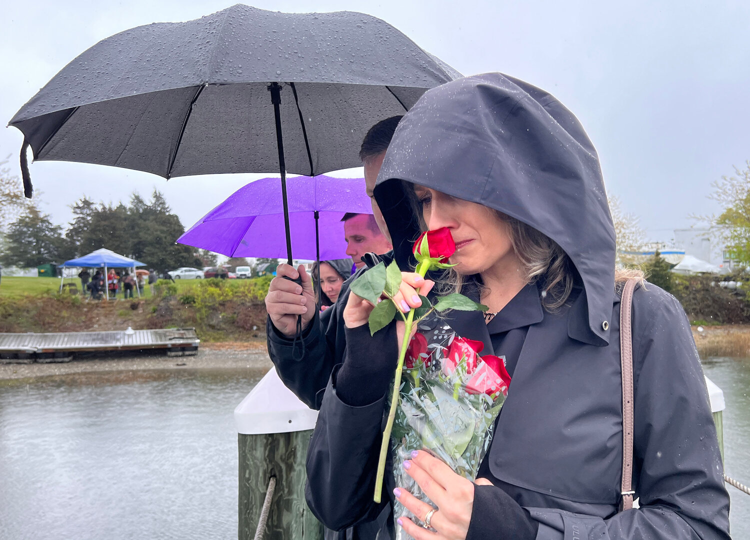 Shannon Watson sniffs a rose before tossing it into Blue Bill Cove Sunday afternoon in memory of her son, Cole, who died at the age of 22 after jumping from the Claiborne Pell Newport Bridge on May 7, 2022. Her husband, Tom, is behind her. They were attending a healing vigil behind Thriving Tree Coffee House in remembrance of those lost to bridge suicide in Rhode Island.