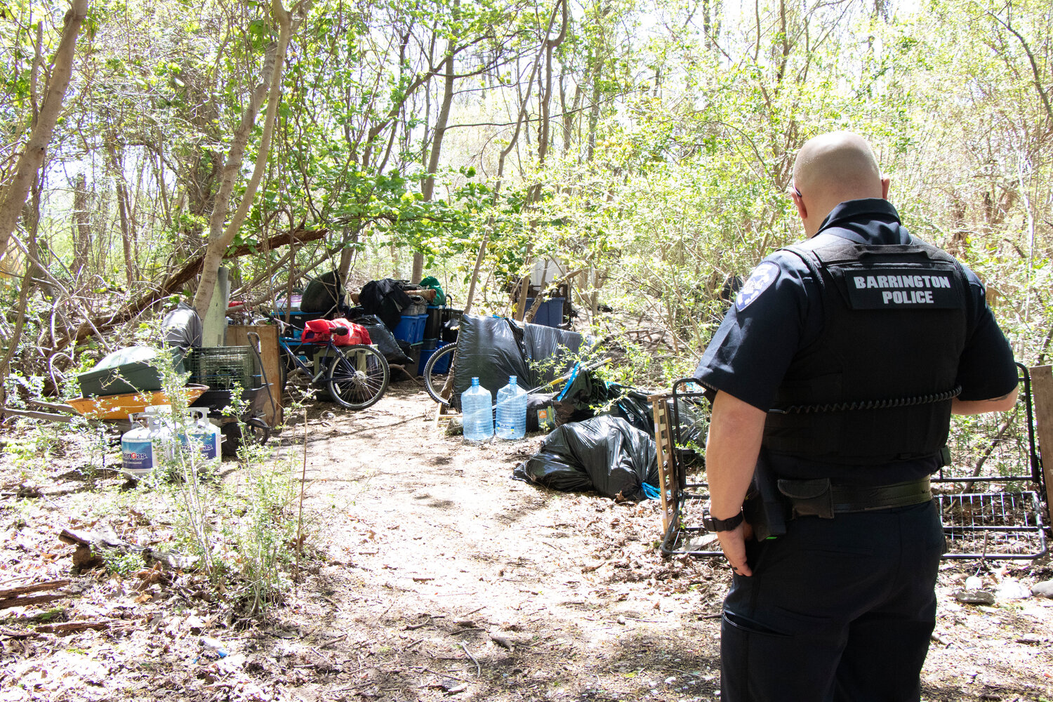 Barrington Police Officer Tim Oser checks the former homeless encampment inside Veterans Park on Monday afternoon, May 1.