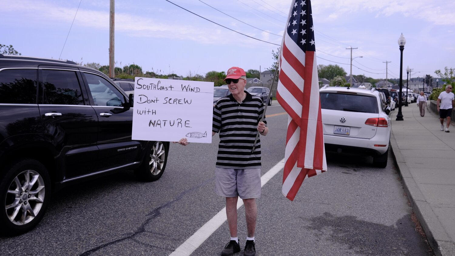 This Portsmouth man who declined to identify himself — “I don’t trust the press,” he said — waved at motorists in front of the rally site while donning a “Trump: Take America Back 2024” hat and flashing a sign that read “SouthCoast Wind: Don’t Screw with Nature” on one side and “God, Guns & Country – TRUMP 2024” on the other. He called President Biden “a nut” for his green energy initiatives.
