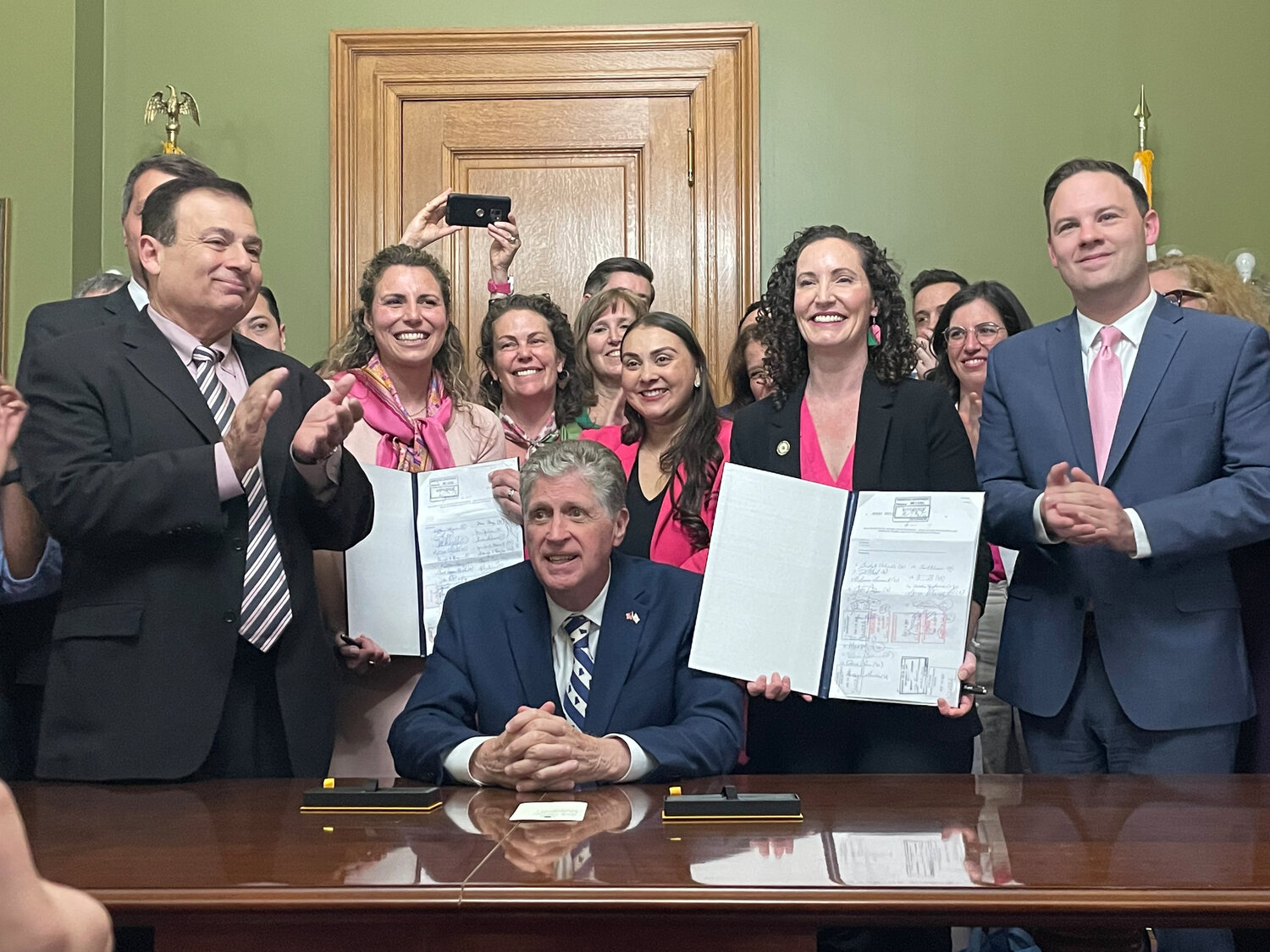 Gov. Dan McKee, seated, signed the Equality in Abortion Coverage Act, with sponsors Katherine Kazarian (D-House Dist. 63, East Providence Pawtucket) , to the left of him holding bill, and Sen. Bridget Valverde, to his right holding bill. At left is House Speaker K. Joseph Shekarchi and at right is Senate Majority Leader Ryan W. Pearson.