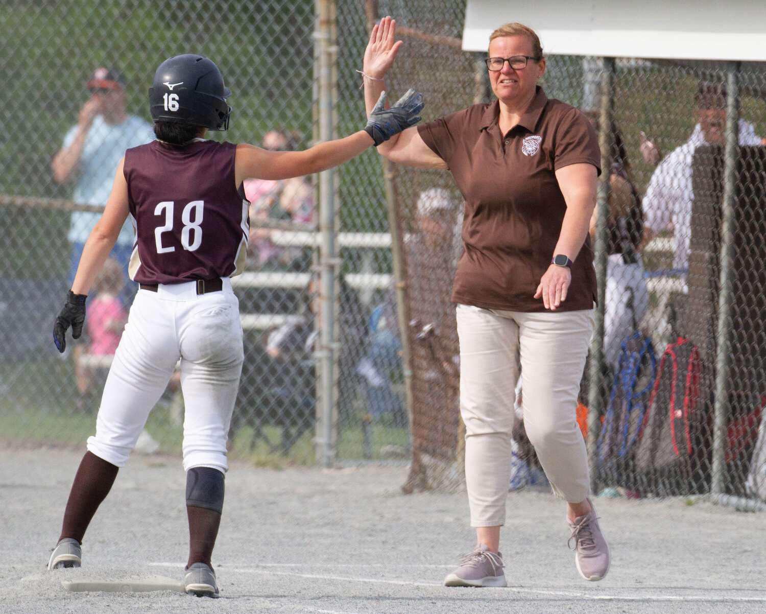 Tess Silvia receives a high five from Wildcats coach Monique Jones after running from first to third on a hit by Makayla Grace.
