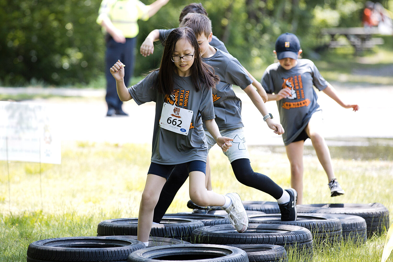 Children run through a tire obstacle.