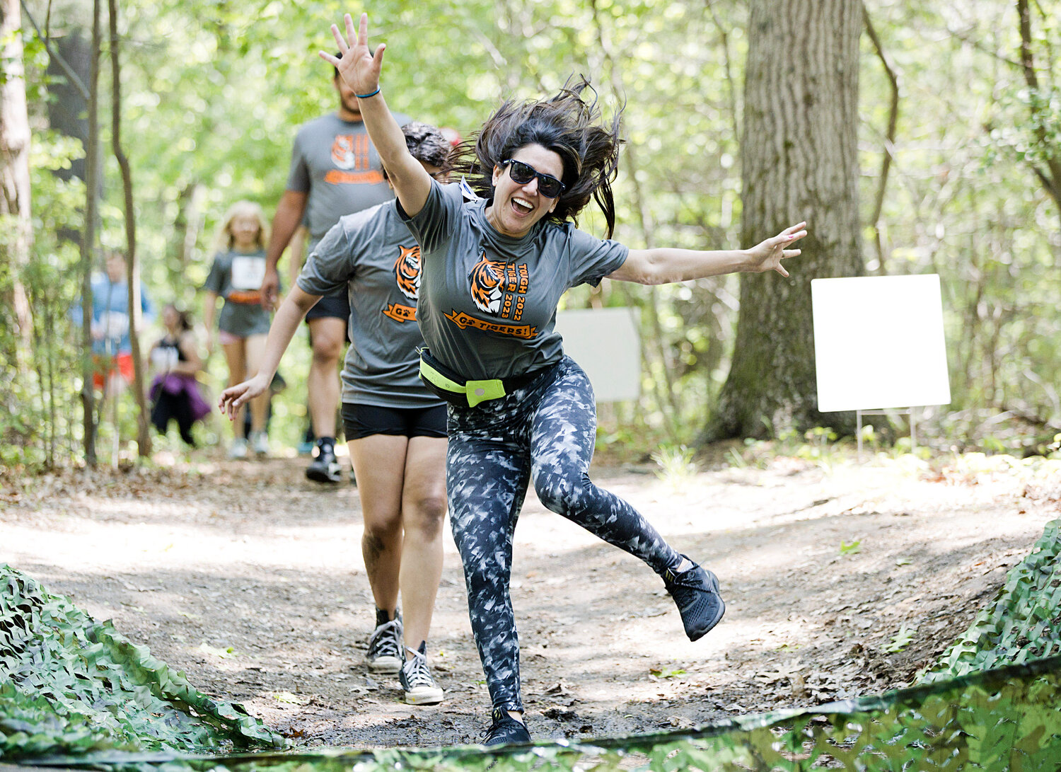 Karen Lanpher takes a dramatic leap into a mud pit while participating in Hampden Meadow's "Tough Tiger" event, Sunday.