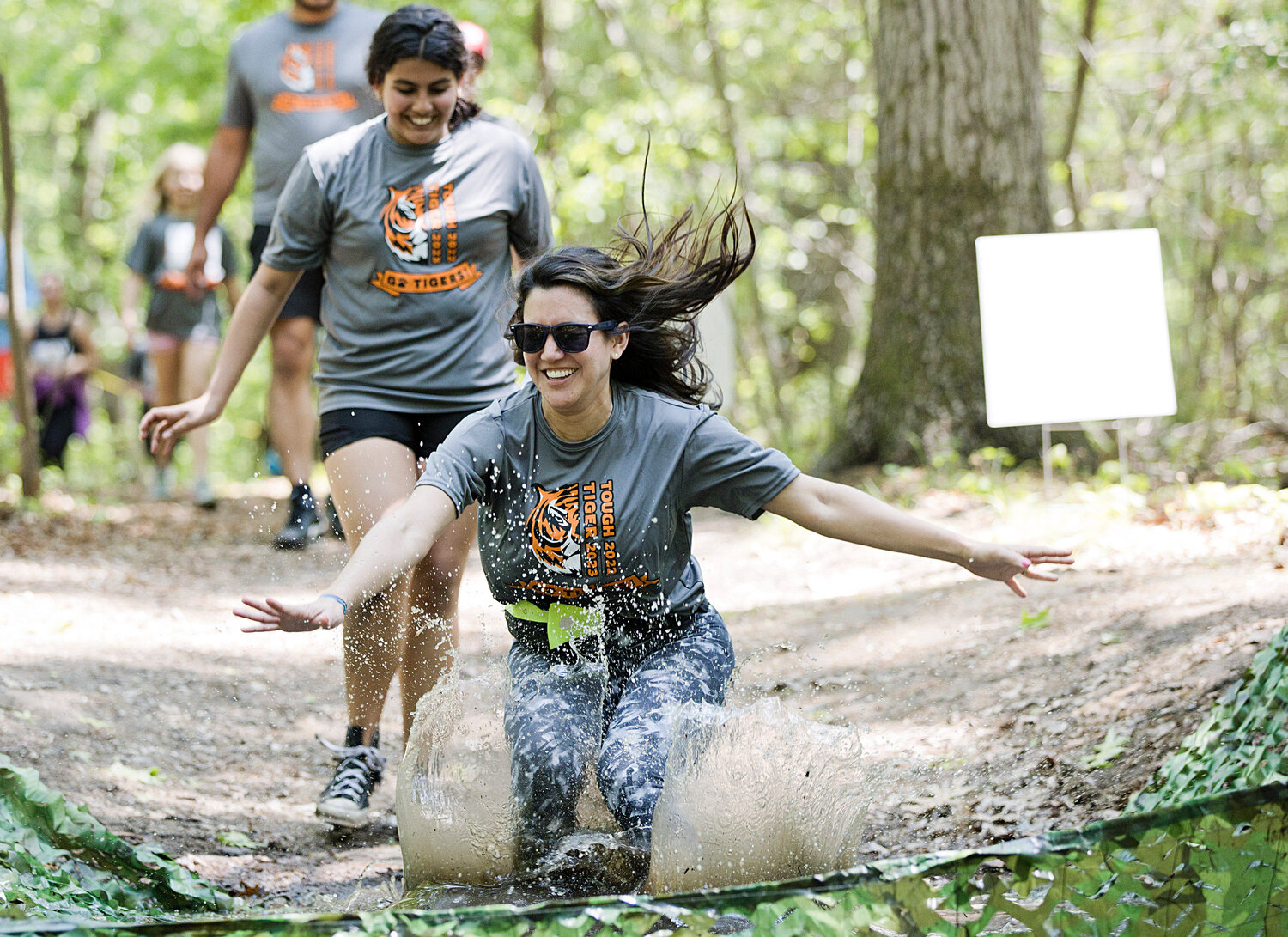 Karen Lanpher takes a dramatic leap into a mud pit while participating in Hampden Meadow's "Tough Tiger" event, Sunday.