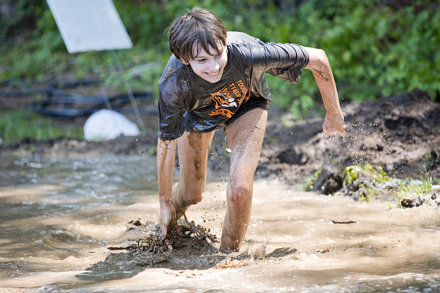 A competitor makes a splash while running through a mud obstacle.