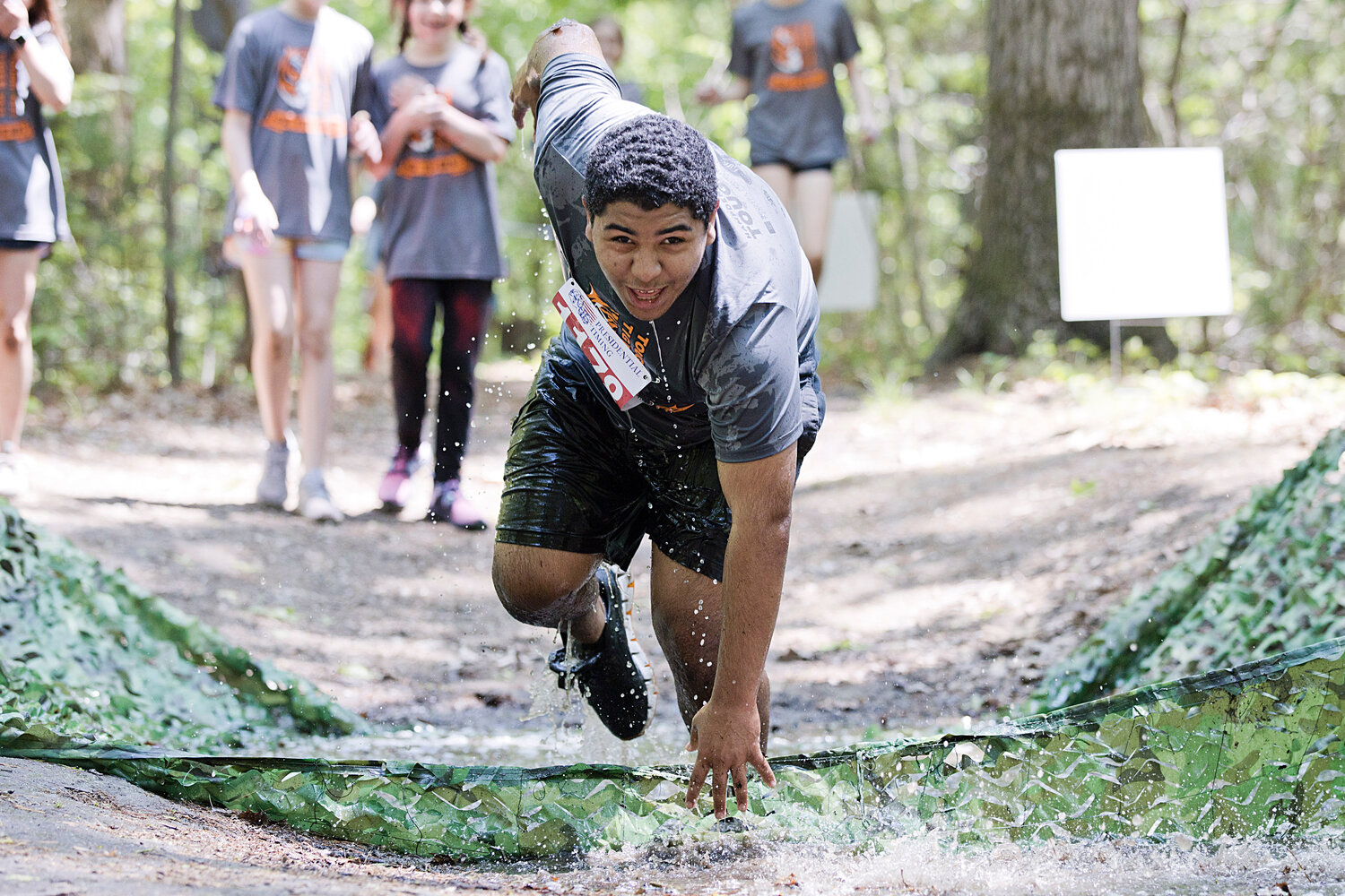 A runner attempts to keep his balance while slipping through a mud pit in the woods, behind Hampden Meadows School.