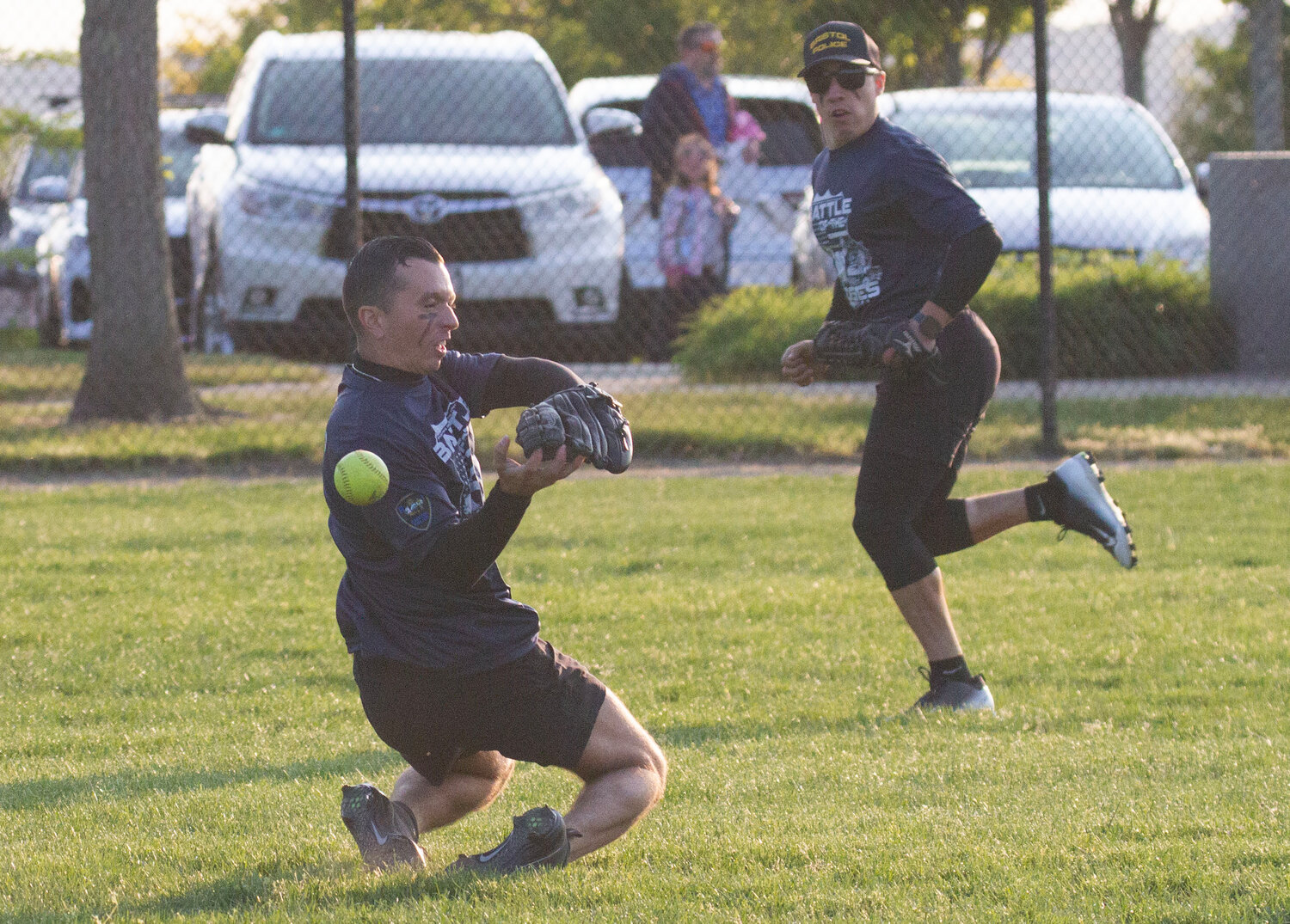Tyler Carreiro (left) attempts to catch a fly ball while another officer backs up the play.