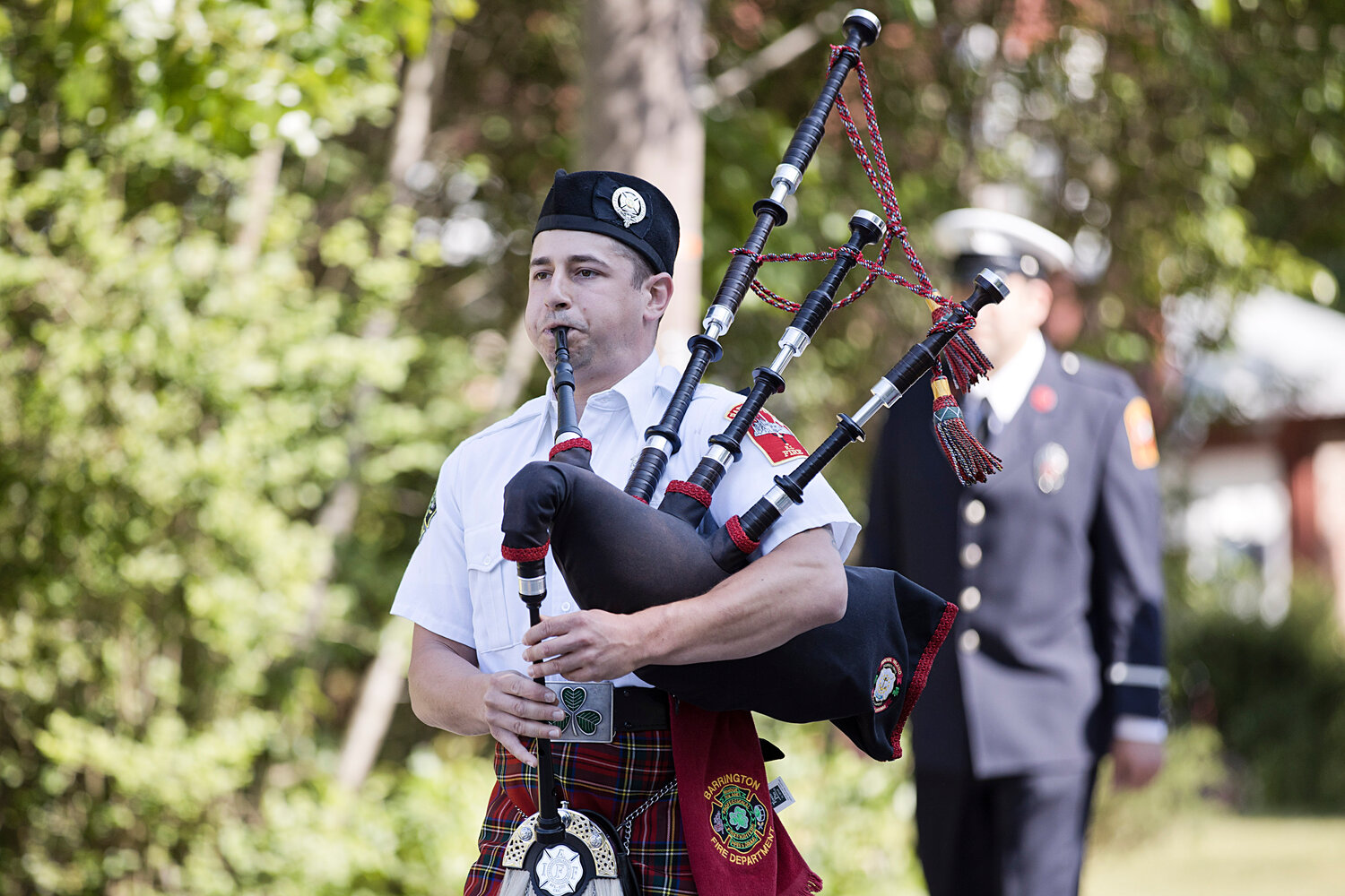 A bagpiper leads members of the Barrington Fire Department along the parade route.