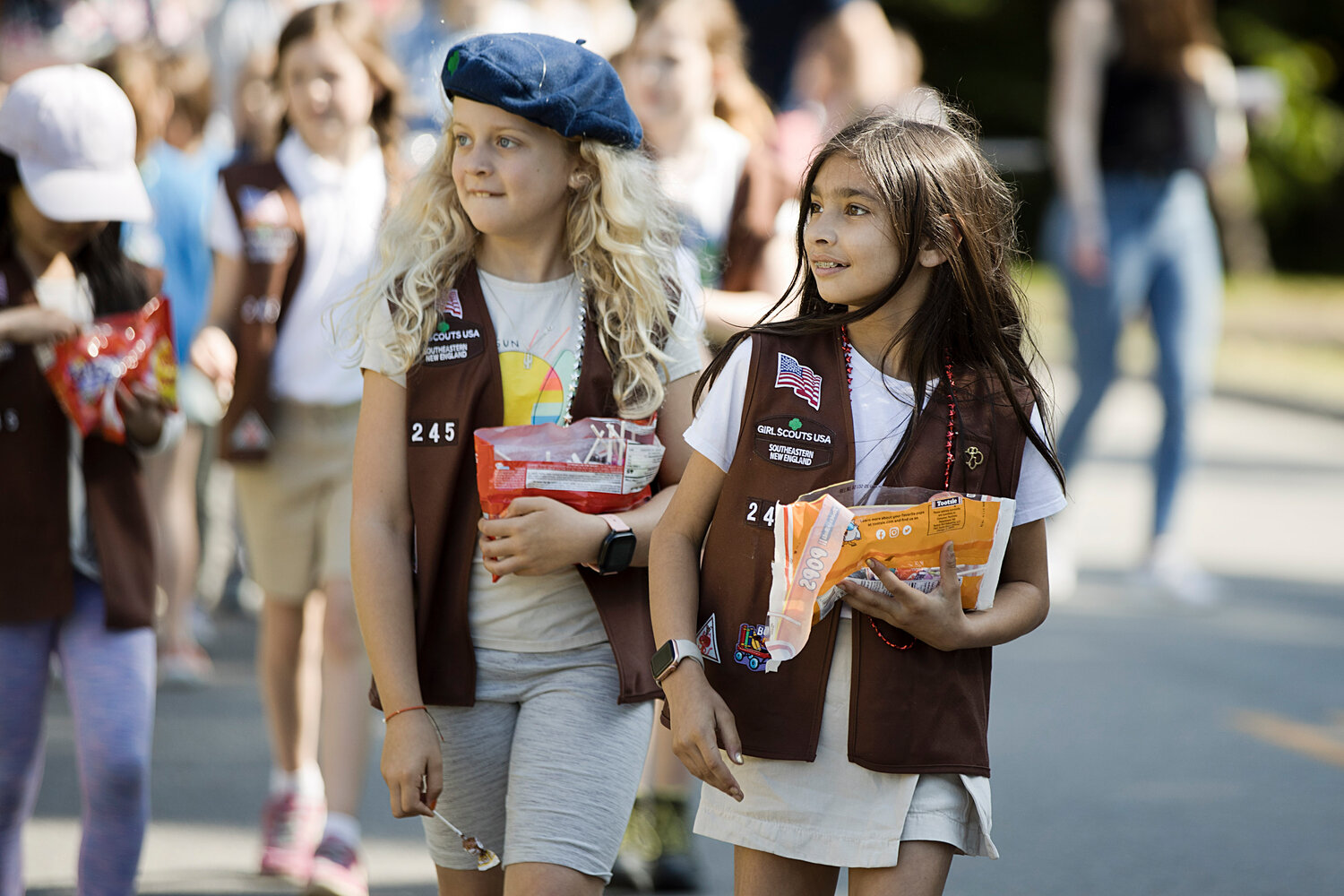 Jane Moores (left) and Sofia Riazi of Brownie Troop 245, throw candy to spectators while participating in Barrington's Memorial Day parade, Monday.
