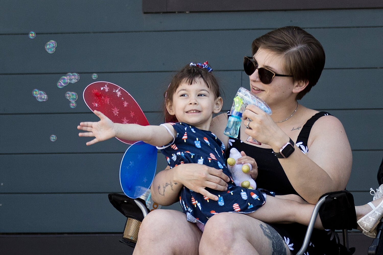 Addaline (left) and Maisie Boucher entertain themselves with bubbles while waiting for the Memorial Day Parade to reach Riverside Square
