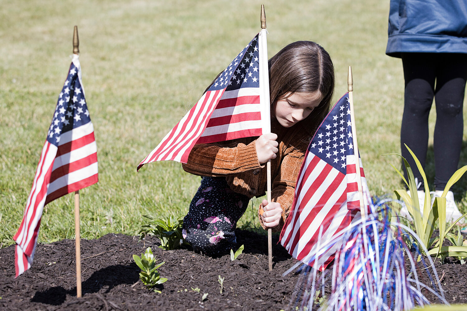 Ocelene Elliot posts a flag in memory while participating in Hugh Cole's Memorial Day celebration.