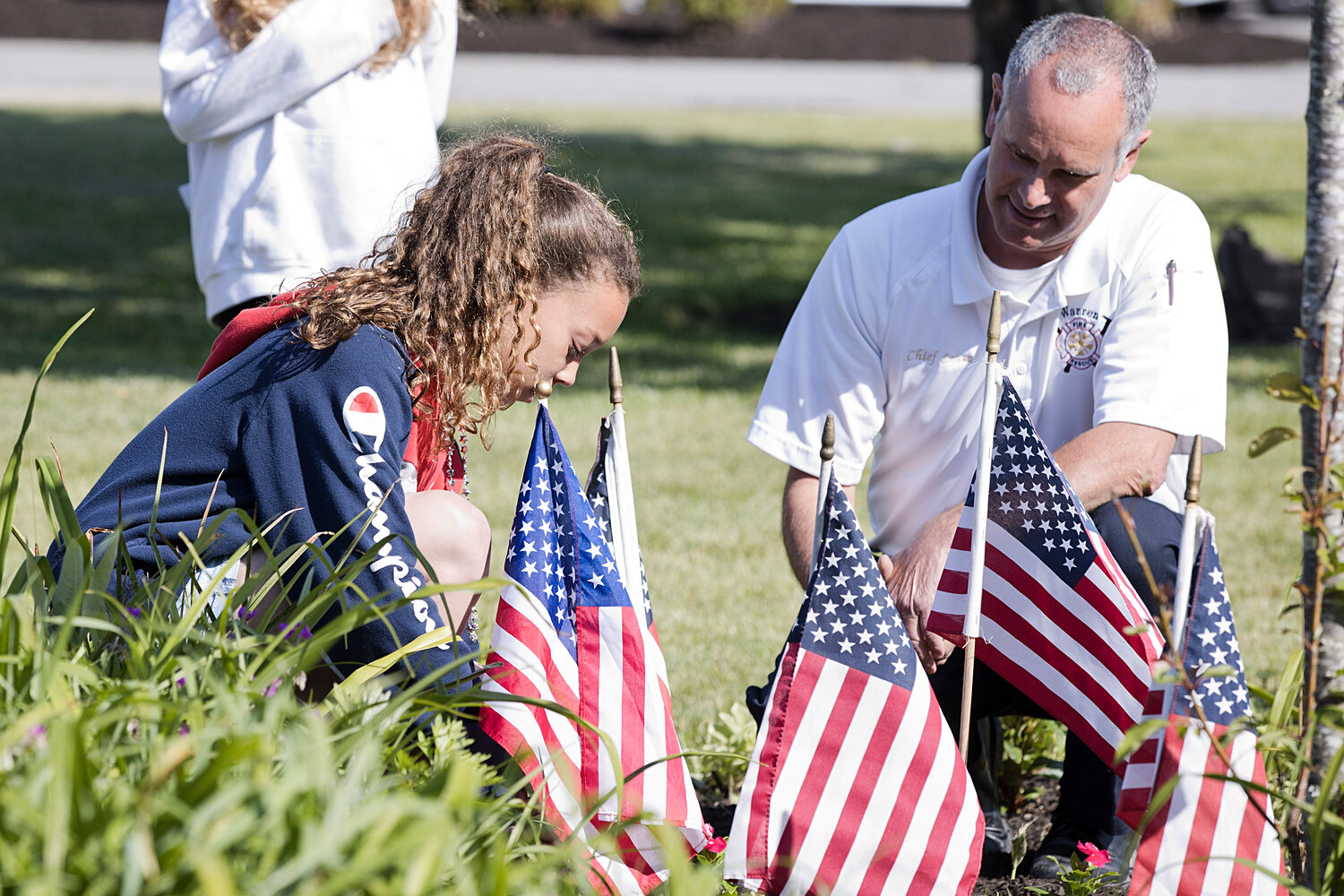 Warren Fire Chief, James Sousa, helps Addison Wilson post a flag in Hugh Cole's Victory Garden.