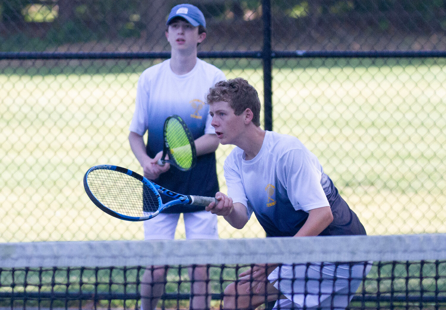Gabe Anderson returns a shot during the playoff match against Mount St. Charles. Anderson's partner, Bryce Kupperman, stands nearby.