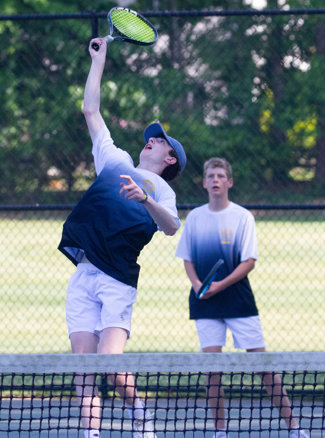 Barrington's Bryce Kupperman reaches for an overhead smash during a doubles match against Mount St. Charles. Gabe Anderson is in the background.