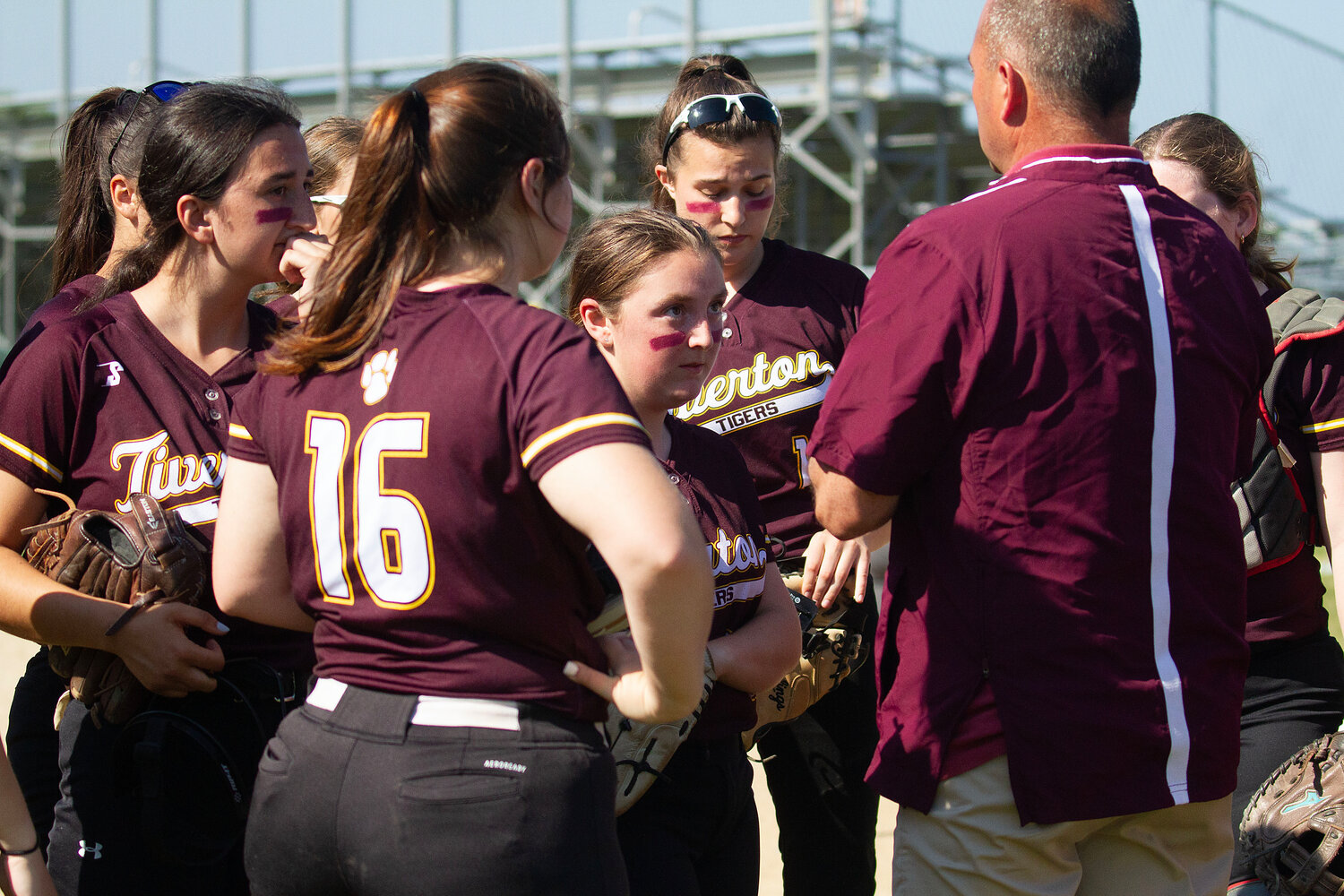 Abbie DeMello (middle) and the team gather around Coach Brigham after the first inning.