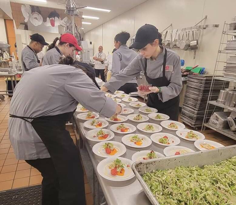 (From left to right) Martim Moniz, Katelyn Bolarinho, Aaliyah Cateano and Teagan Abatiello prepare what became their 2023 Rhode Island High School Seafood Cook-Off competition winning entry "Lemon Steamed Summer Flounder with a Brussel."