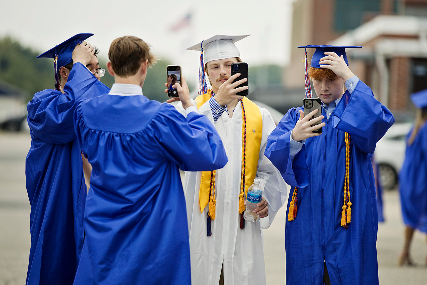 Class of 2023 Vice President Nicholas Waycuilis (white robe), Jake Grier (right), and two other friends make sure their hair is in place before walking the stage at Portsmouth High School’s graduation ceremony Friday night.