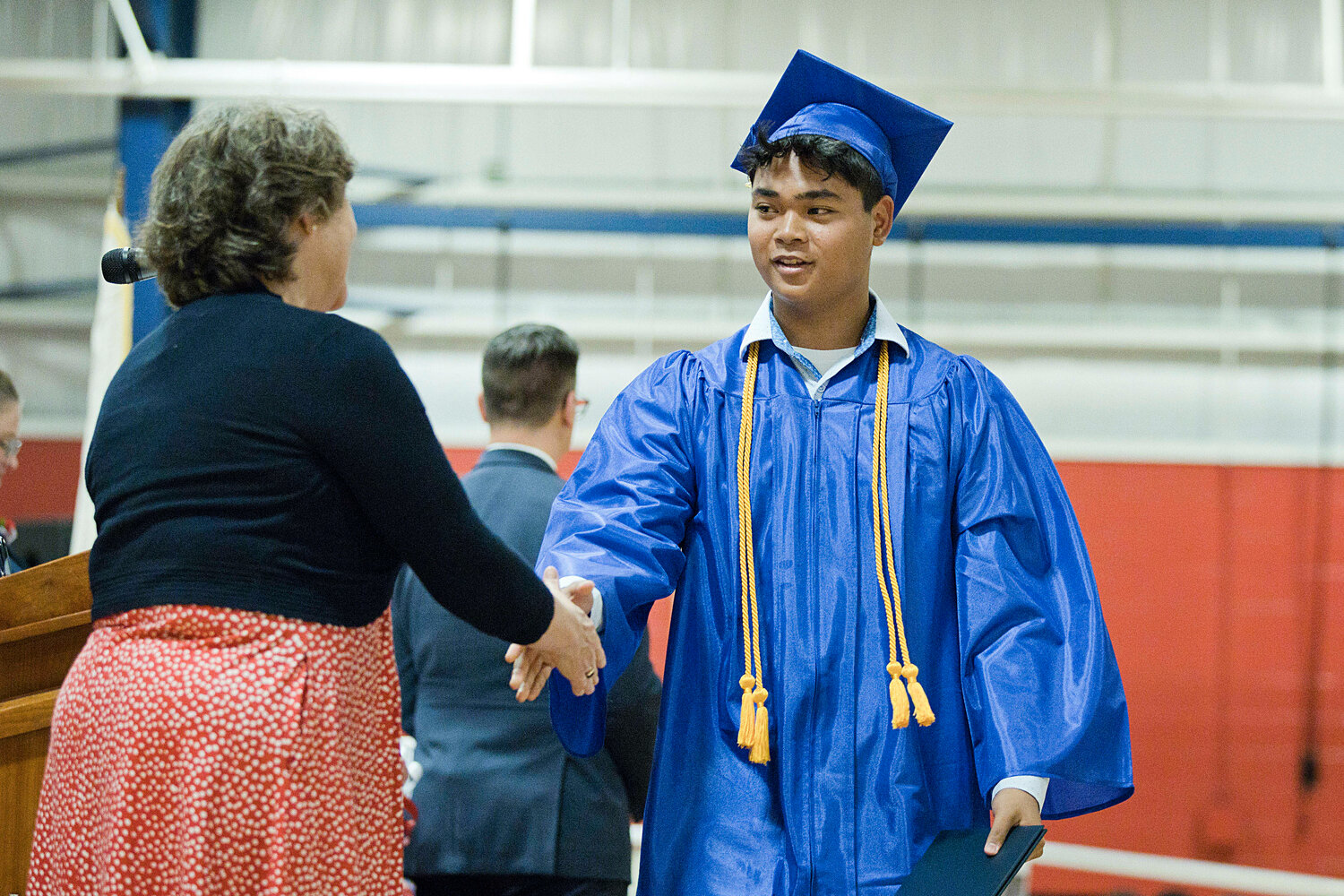 Trey Delemos shakes hands with Portsmouth School Committee Chair Emily Copeland after receiving his diploma.