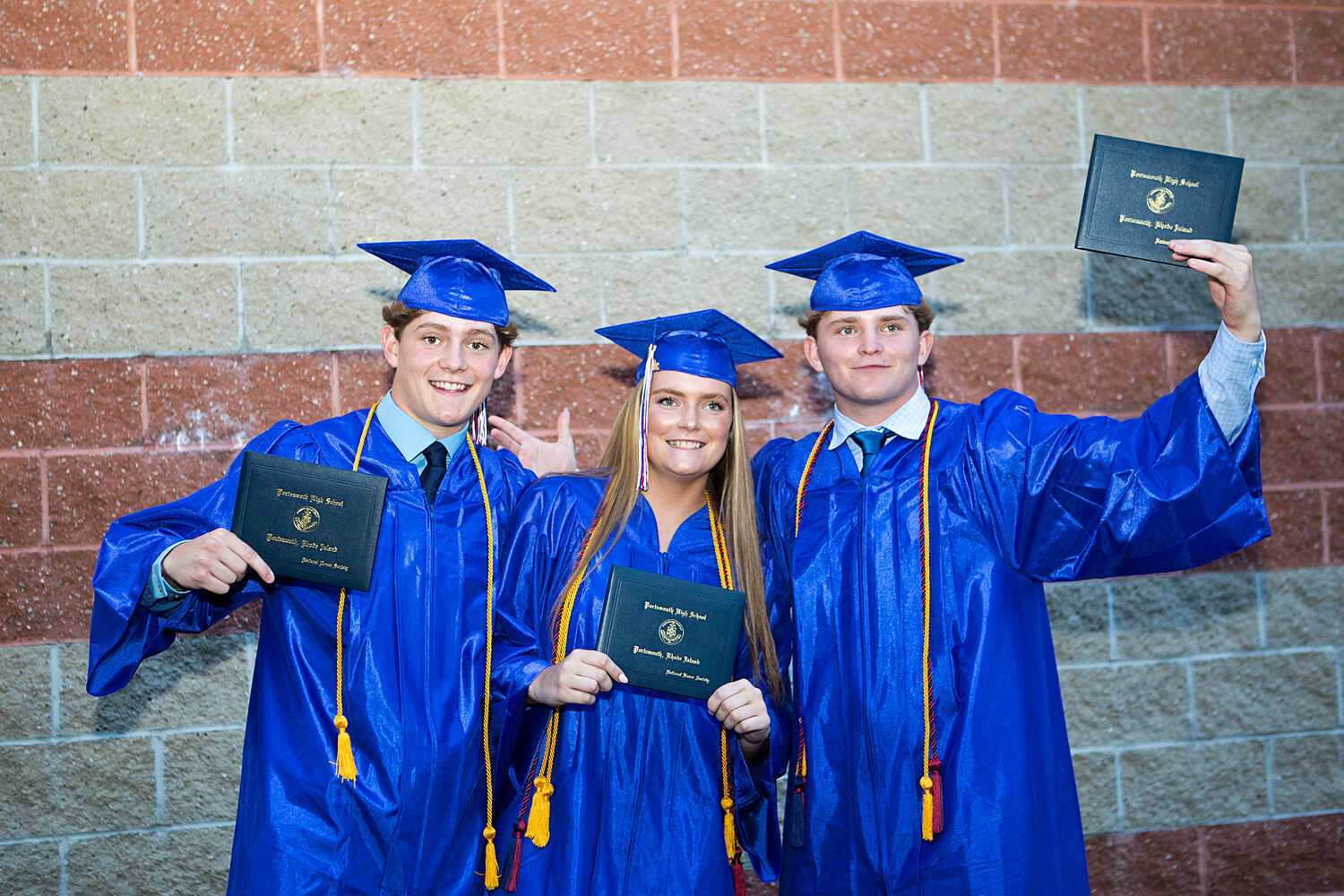 The Tullson triplets from Little Compton — Evan, Maeve, and Neal (from left) — show off their diplomas after graduating from Portsmouth High School Friday night.