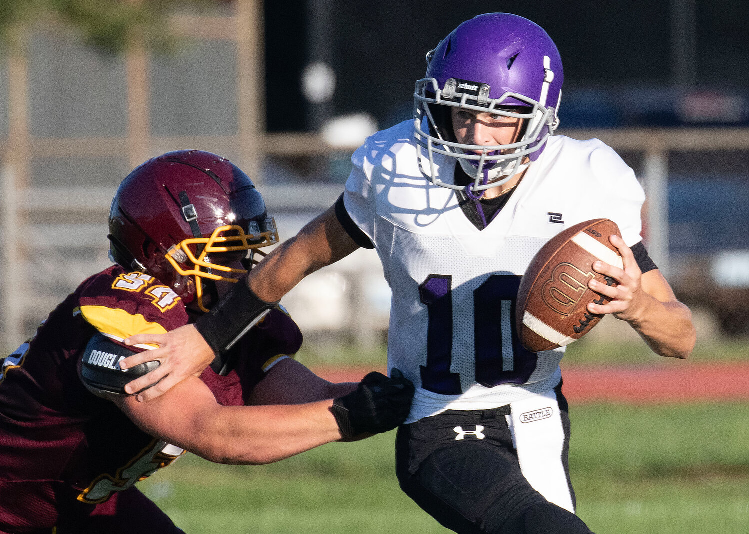 Huskies quarterback Ethan Martel brushes off a Tiverton defender while looking to make a pass during Mt. Hope's 21-0 victory over Tiverton during an injury fund game in Barrington on Thursday night.