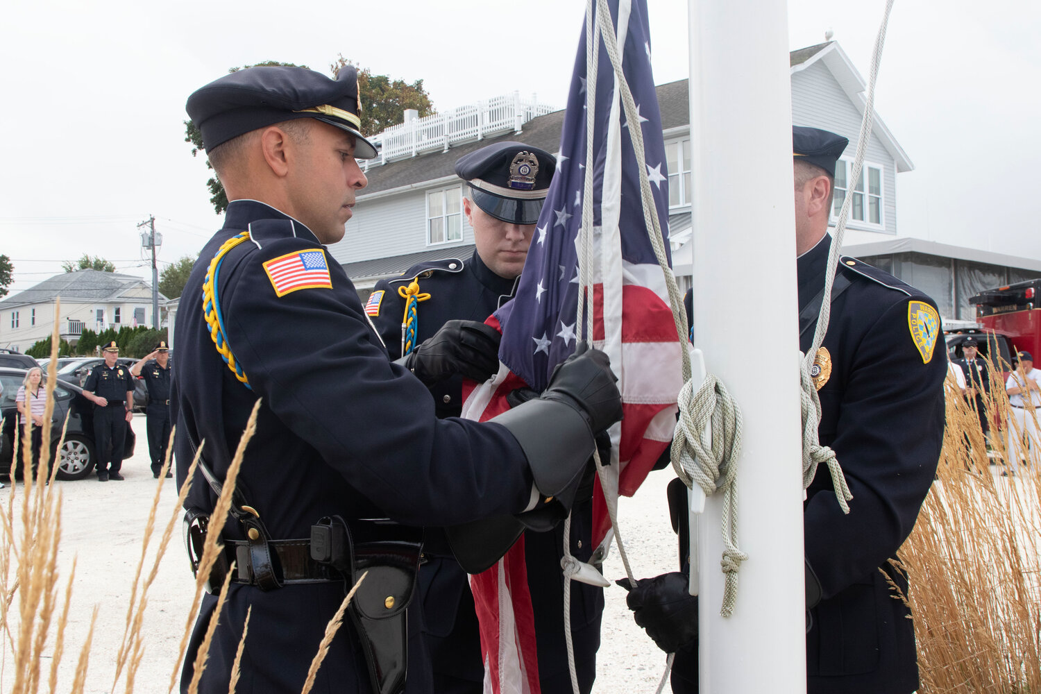 Warren police color guardsmen, Sgt. Joel Morrissette (left) patrolman Lane Ukura and Det. Donald Lanoie, attach the flag to the flag pole to be flown at half-mast.