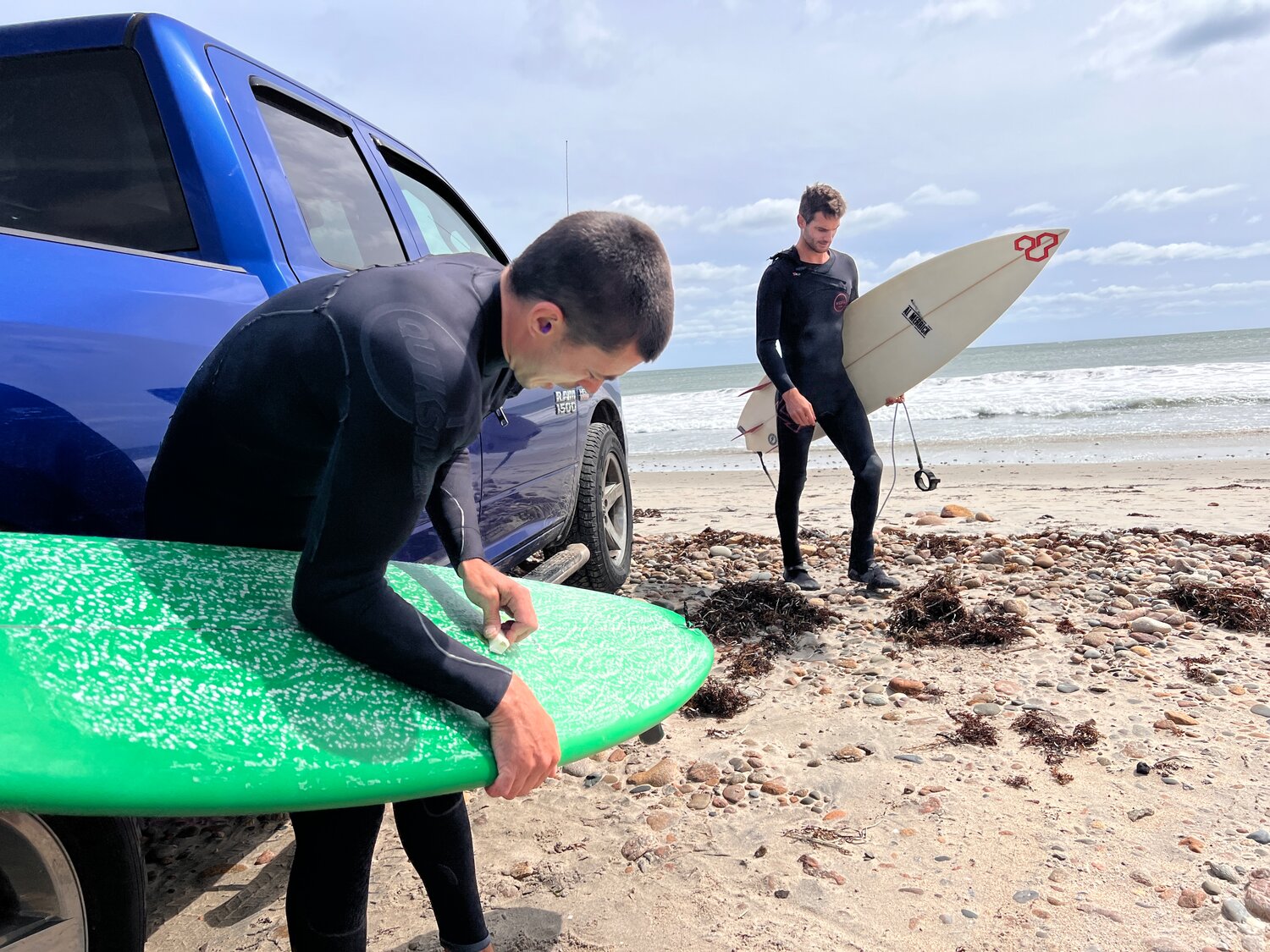 Jaycob Davidson (left) applies wax to his board in preparation of hitting the surf at South Shore Beach on Friday. Jesse Gould is right. 
Jesse gould