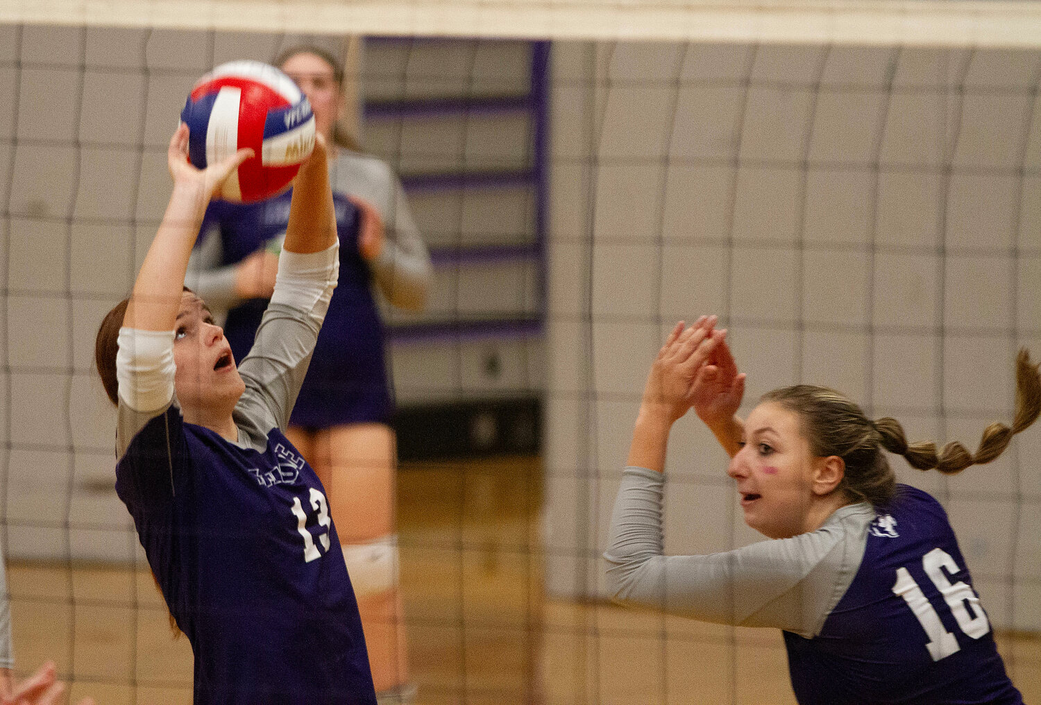 Senior Mia Shaw (left) sets the ball to a teammate while hitter Abby Allen dekes around her.