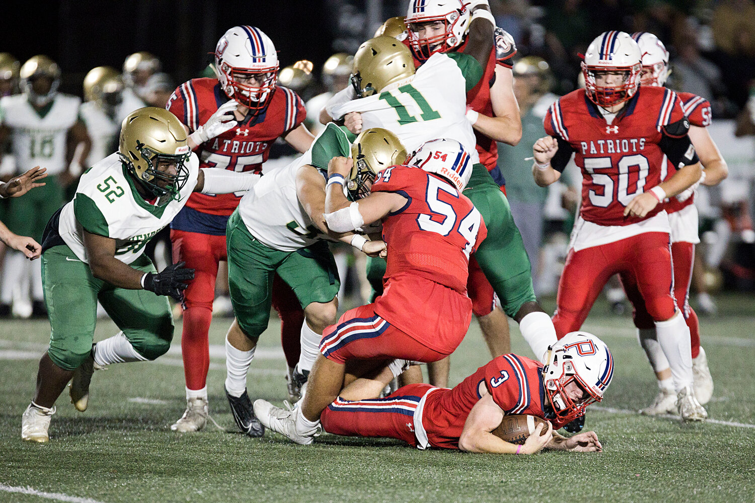 Jack Voute (on the ground) dives through the Hendricken defense to gain yardage for the Patriots.