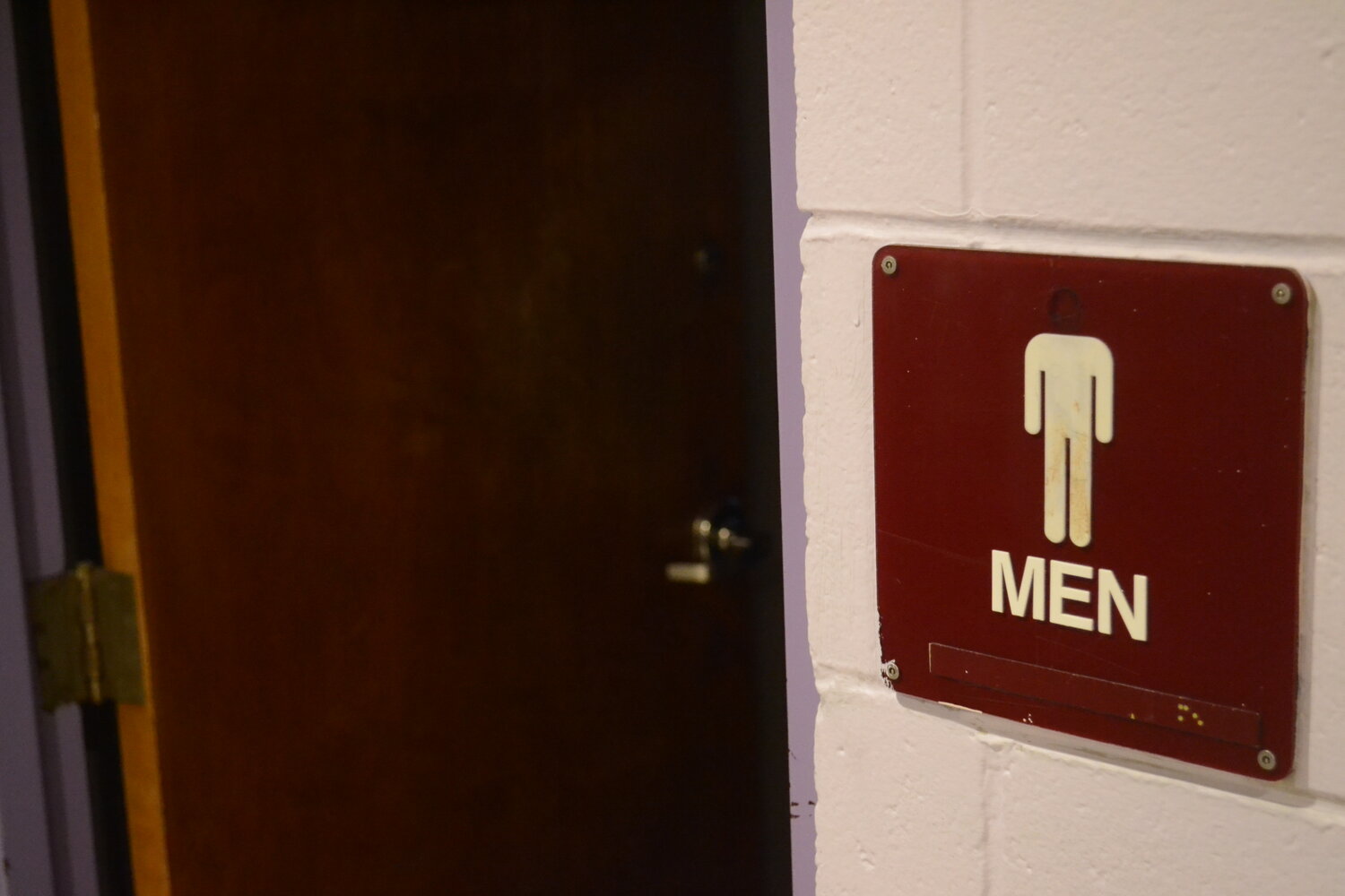 A sign outside one of the boys restrooms missing its head.