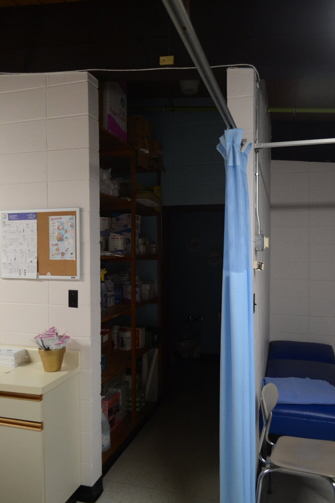 A bathroom in the nurse's office does not comply to the ADA, since a wheelchair cannot physically fit in the corridor.