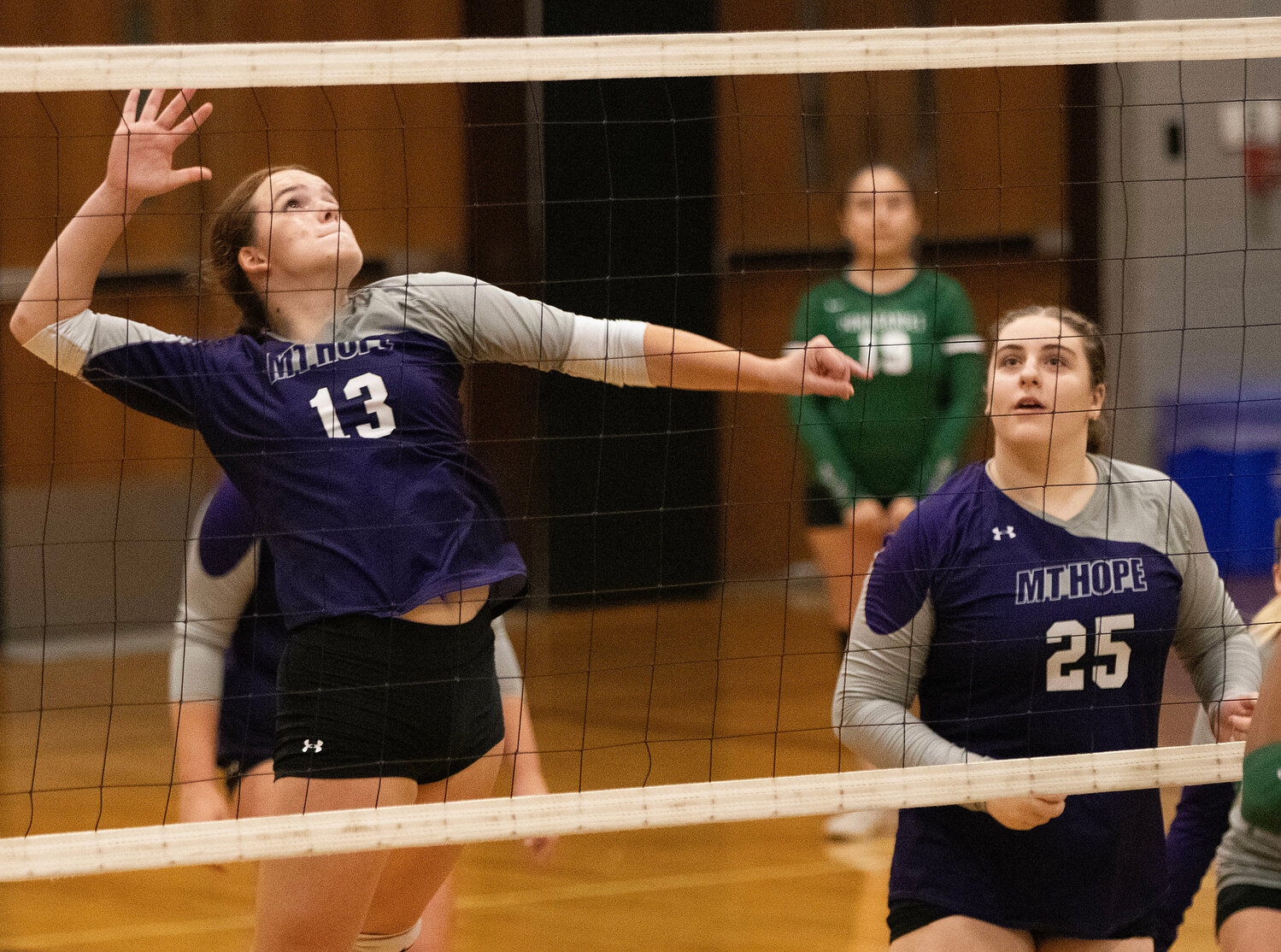 Mia Shaw (left) elevates to spike the ball with teammate Gianna Lunney looking on.