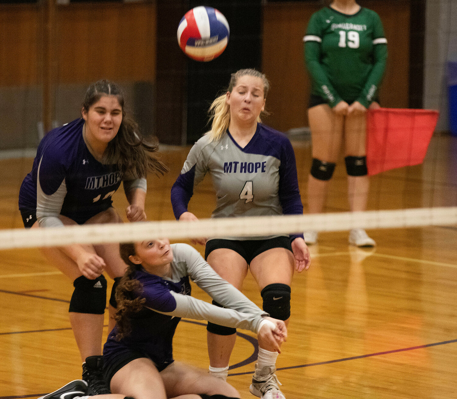 Leah Marshall (left) looks on as Savannah Murray volleys the ball from her knees, with Mia Hanson (right).
