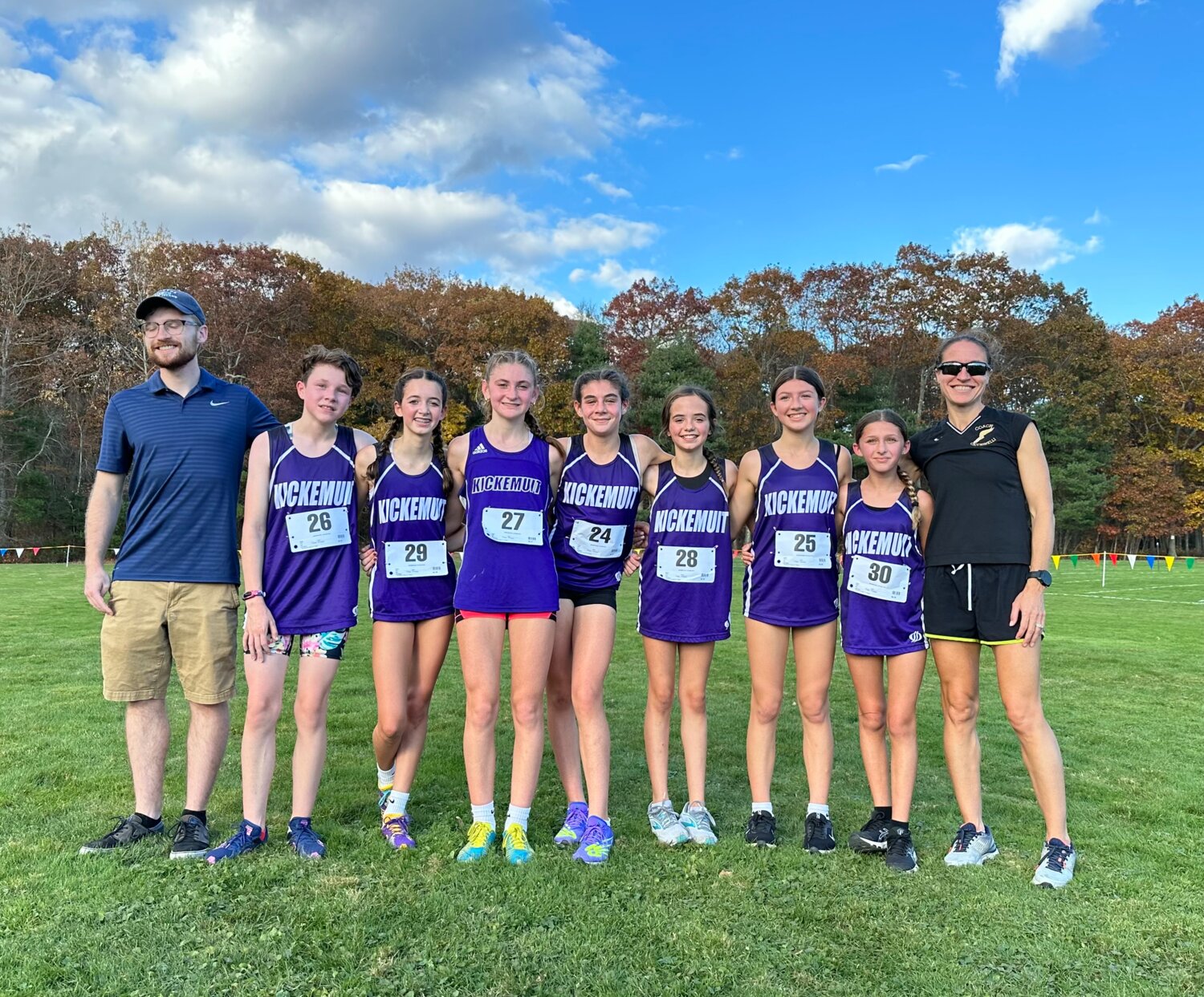 Members of the Kickemuit Middle School girls’ cross country team, with Eleanor Lial (middle, bib number 27) and coach Renae Cicchinelli (far right).