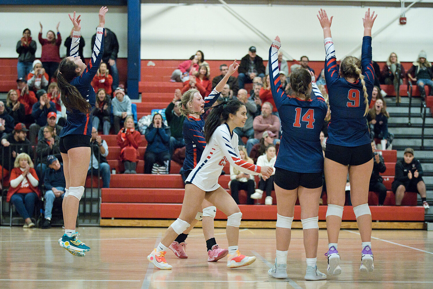 The Patriots celebrate after battling back to win the third set 25-23.