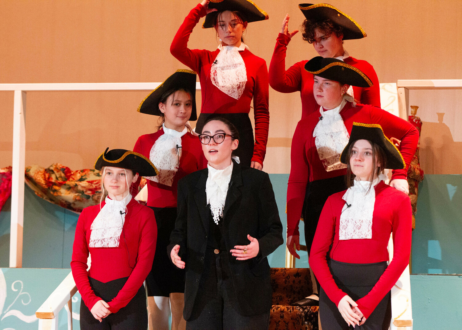 Theresa Katin (center), playing Antonio Salieri, is surrounded by citizens of Vienna played by (clockwise from lower left) Fiona Sarro, Olivia MacPhee, McKenzie Loyola, Elizabeth Viveiros, Julia Victor, and Kaylee Hagerty.