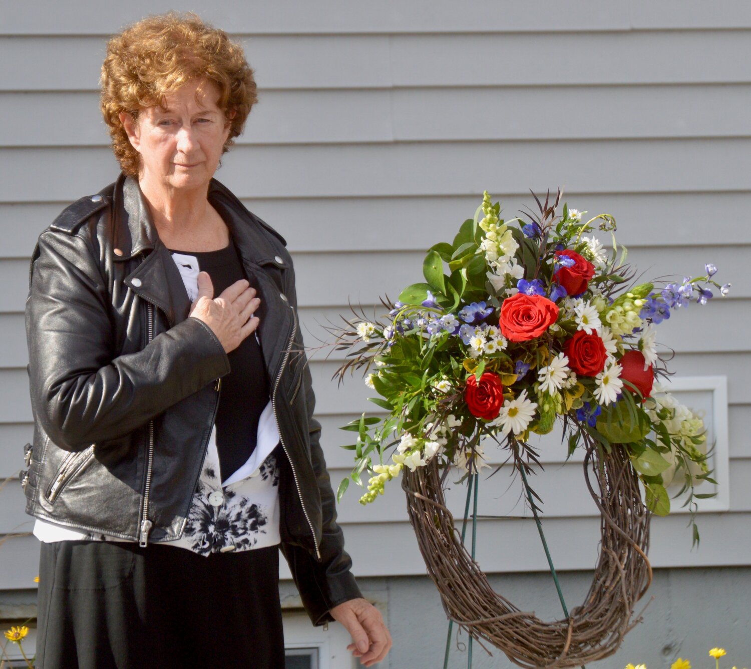 Carolyn Evans-Carbery of Project Blue Star pauses during the playing of “Taps” after she placed a wreath outside the VFW hall following the indoor portion of the ceremony.