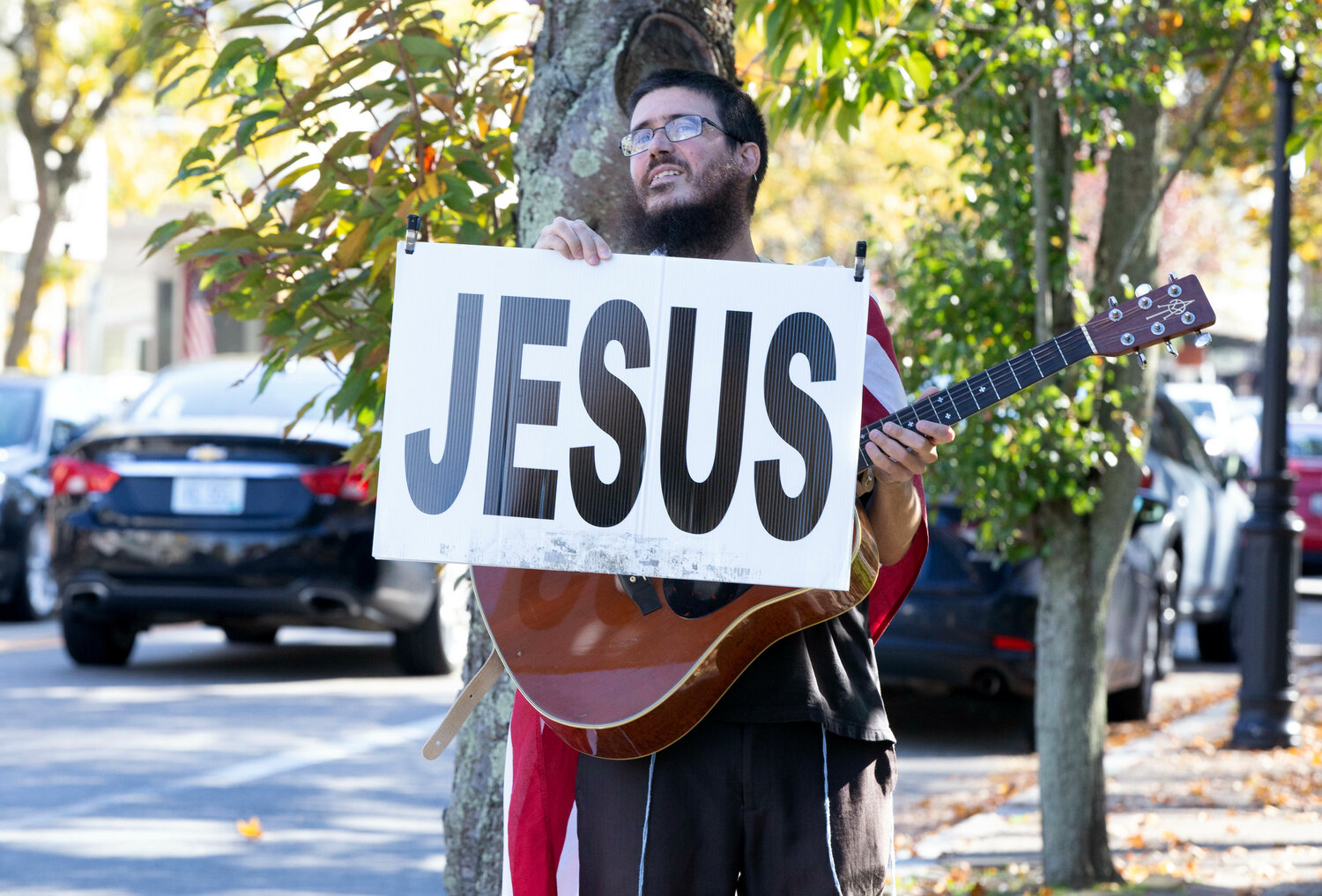 Nathaniel Dempsey, 41, of Warren, plays guitar and totes his Jesus sign on Main Street in Warren.