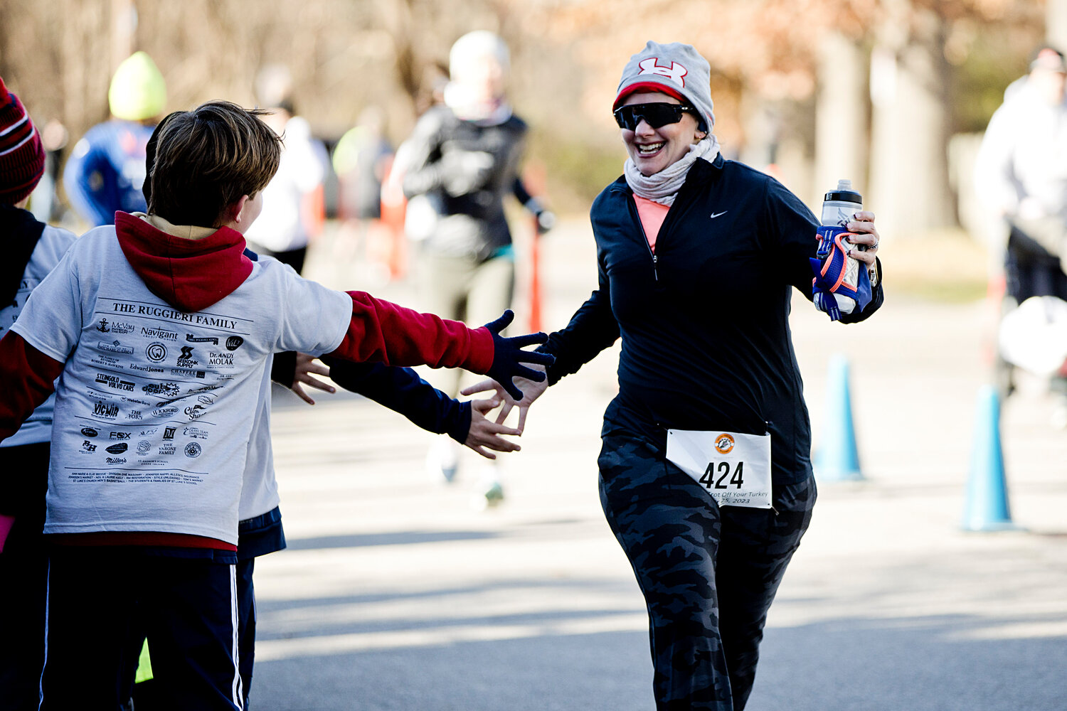 Kara Lees receives high-fives as she races toward the finish line of the 24th annual Trot Off Your Turkey 5K.