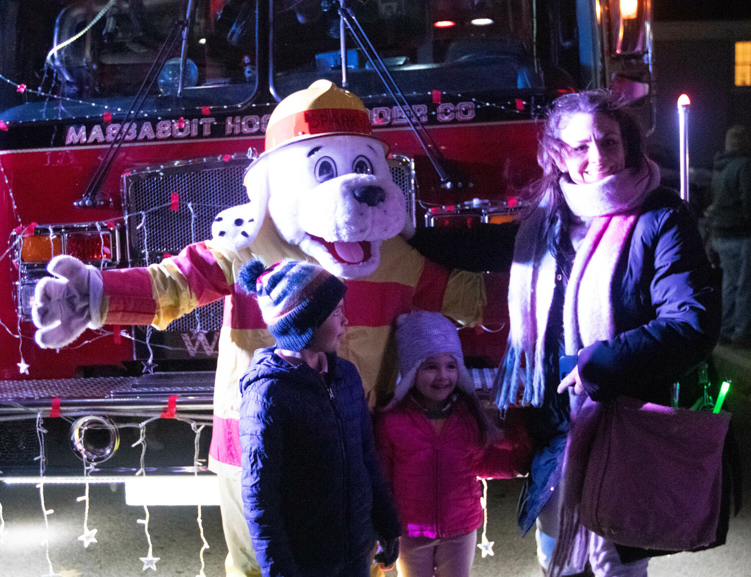 Sparky the Fire dog takes a photo with a family in front of ladder one.