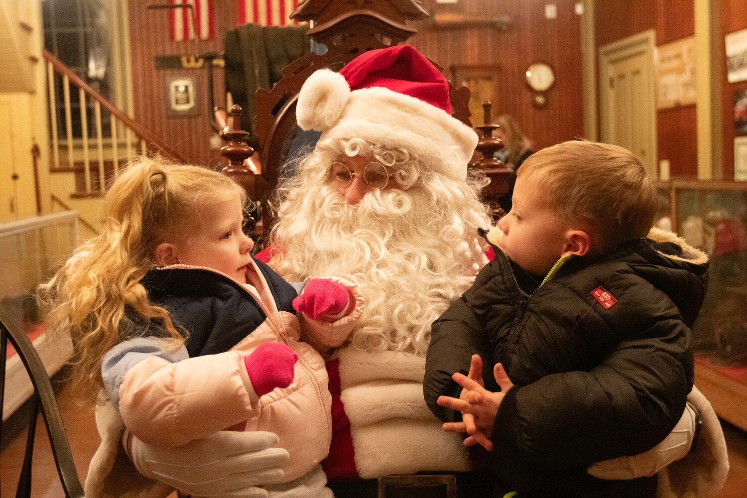 Stella Archambault,  3, and brother, Leo, 4, sit on Santa's lap at the Fire Museum.