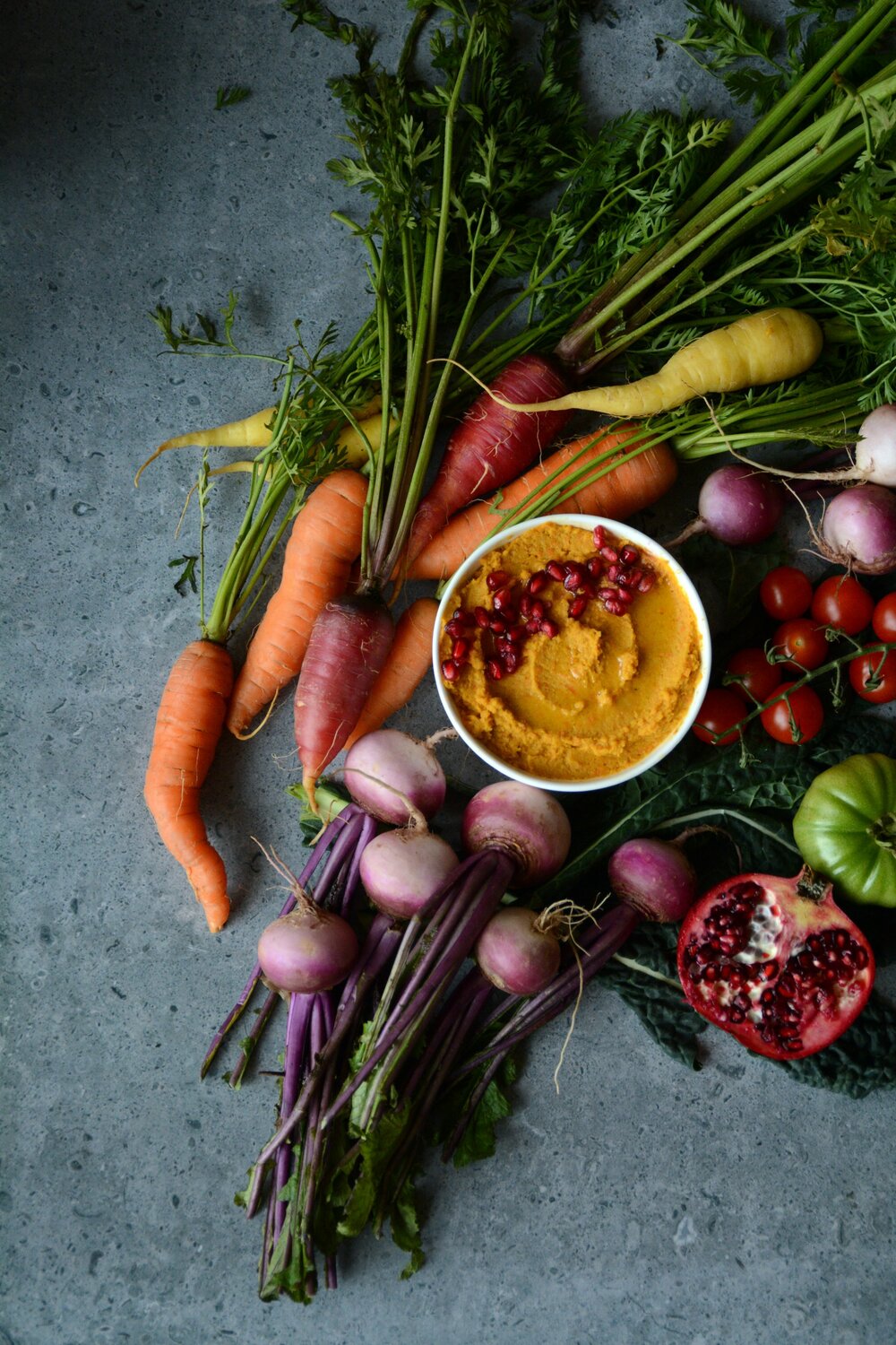 With vibrant colors and loaded with nutrition, foods like carrots, purple top turnips, tuscan kale, tomatoes, pomegranate, and a carrot hummus make a striking presentation.