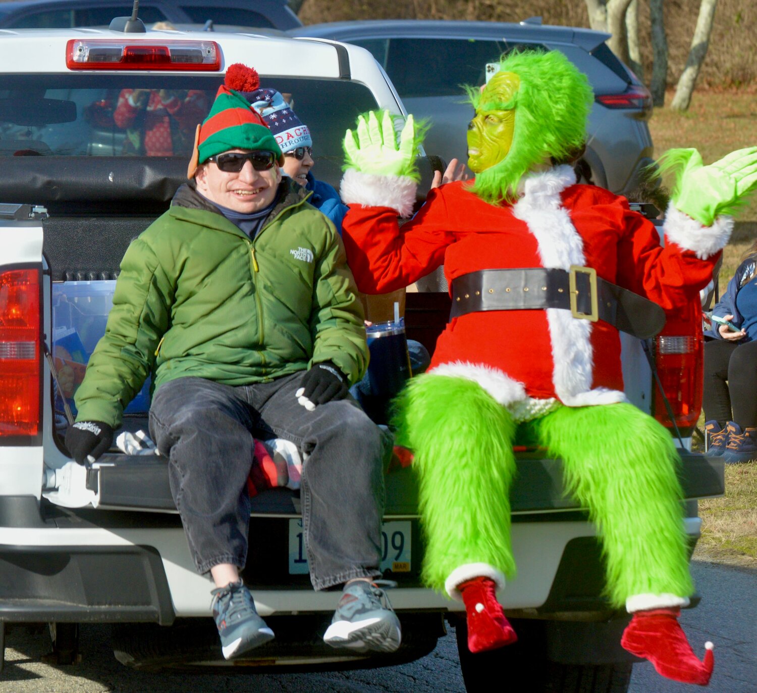 Jared Tierno, Ruth Faria (obscured), and Olivia Garcia as the Grinch (from left) greet passersby during the mini-parade.