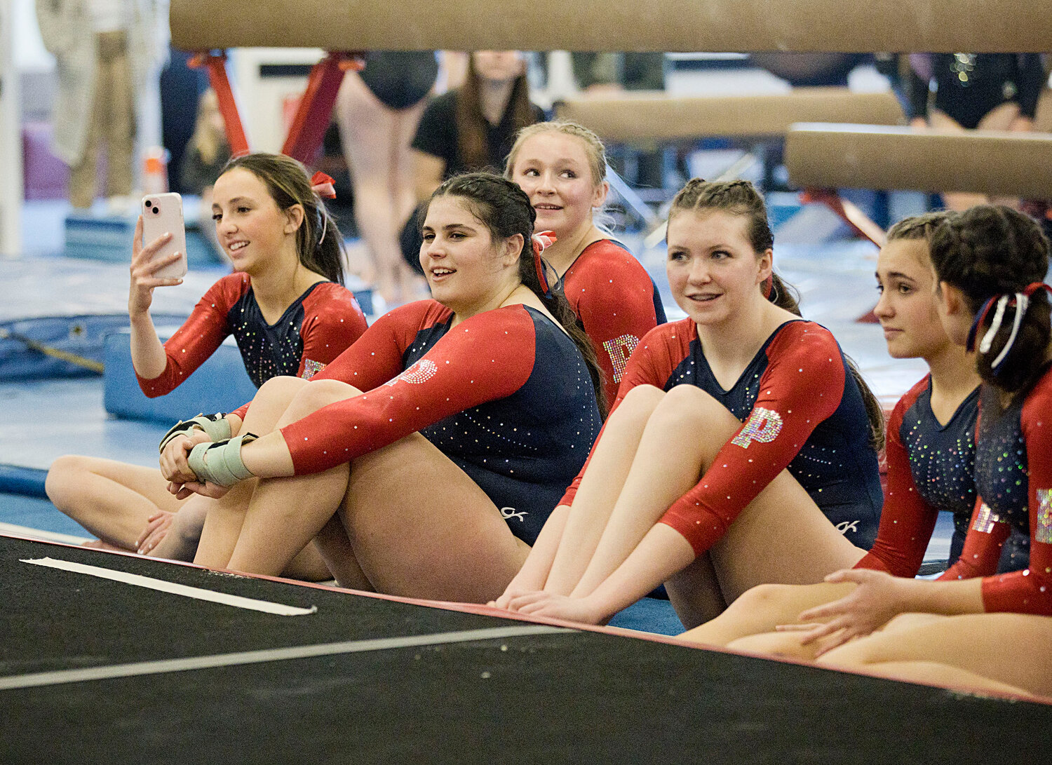 Portsmouth gymnasts look on as a teammate competes on floor.