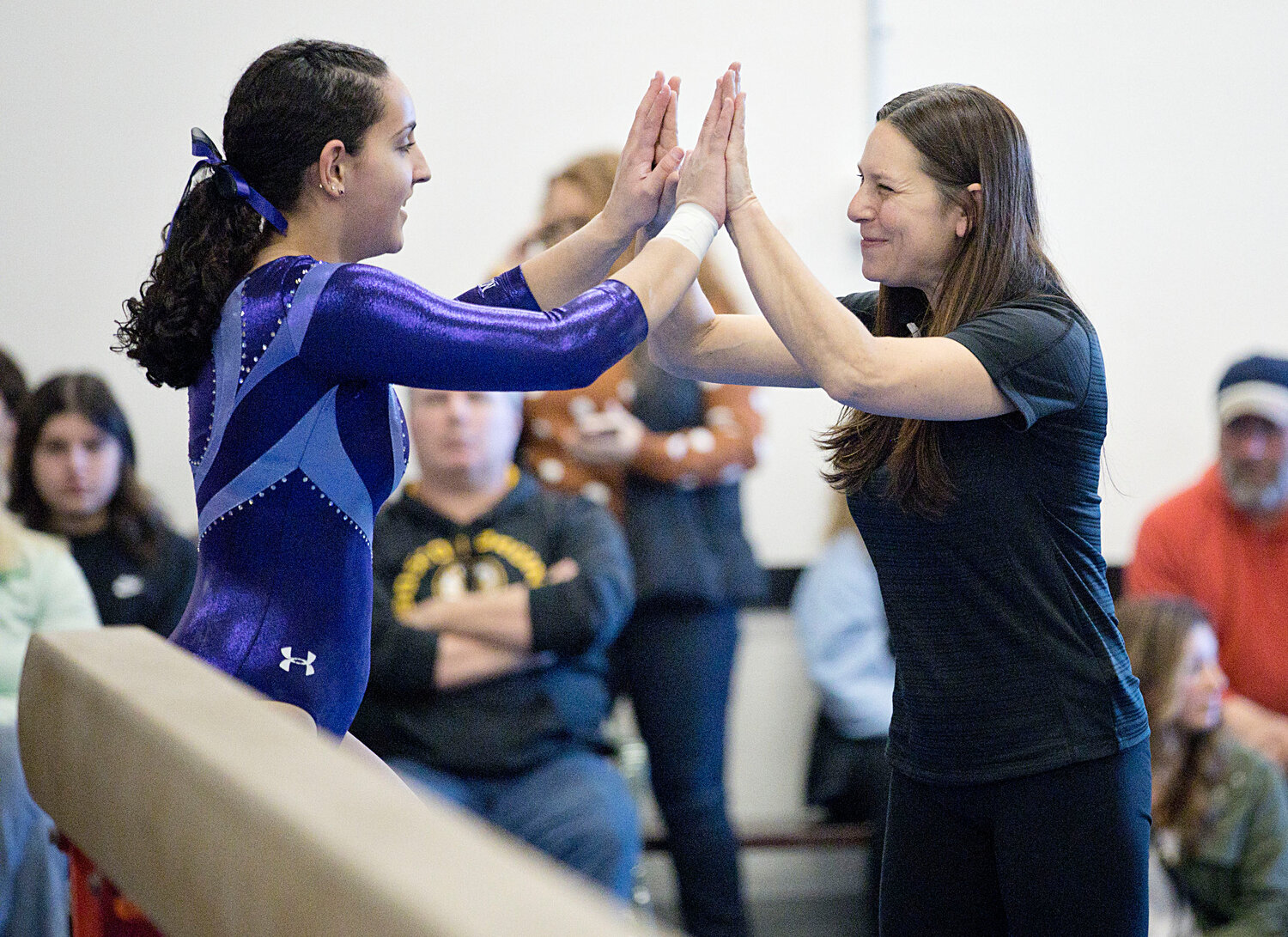 Head coach, Nicole Danielo, high-fives Sarah Sustakowsky after her efforts on beam. 