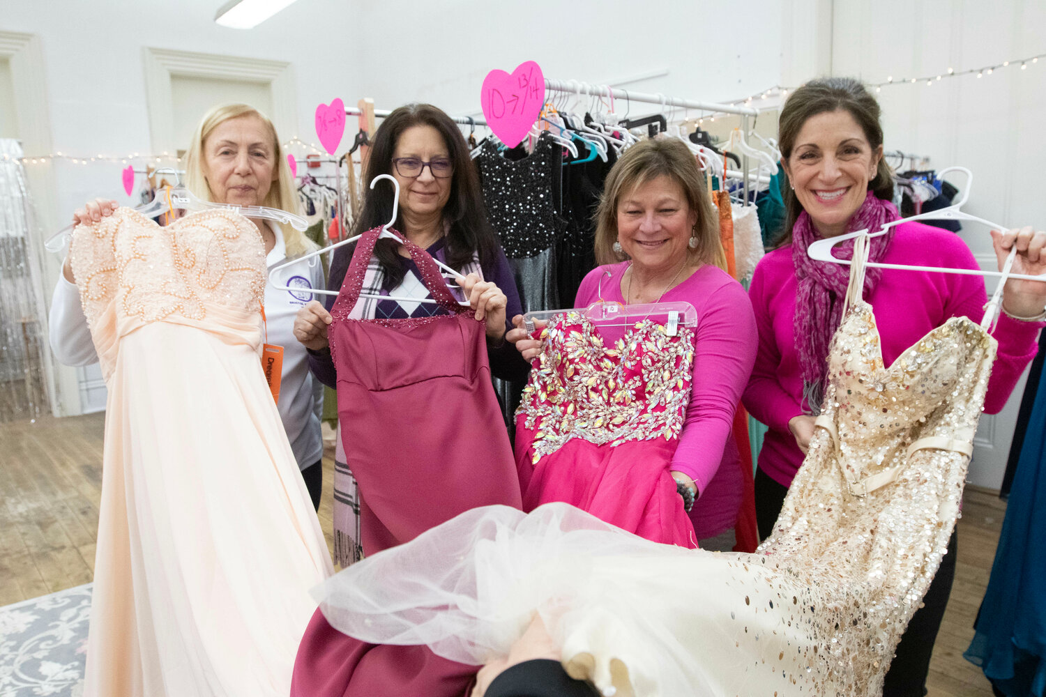 Cathy Keighley (left), Michelle Medeiros, Gina DiSano and Deb Coccio hold up prom dresses.