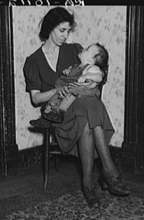 Wife of Homer Sharer and the baby, one of five children. Former tenant farmers and hired hands. They are now living on unemployment relief in Estherville, Iowa - Photograph by Lee Russell, part of the Farm Security Administration Collection