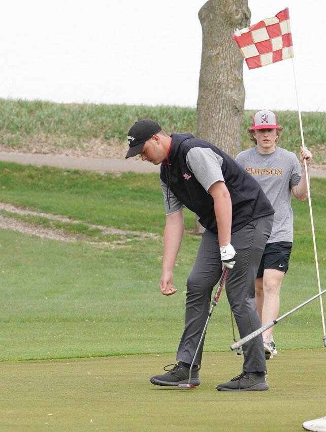 ELC&rsquo;s Carter Ingvall reaches for his ball after completing Hole No.. 2 at the Estherville Golf Course on Friday, May 2. Teammate Blake Evans prepares to return the flag.
