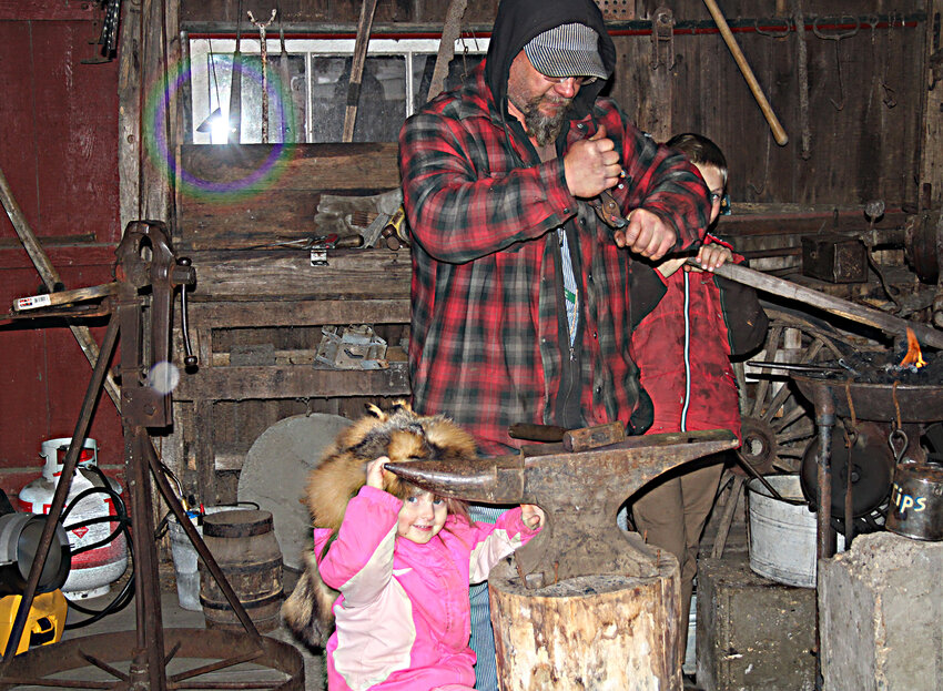 The Blacksmith&rsquo;s daughter, with coonskin hat, sold blacksmith merchandise and assisted with the shop. Lawrence Hacker of Jackson, Minn. was the blacksmith for the event.