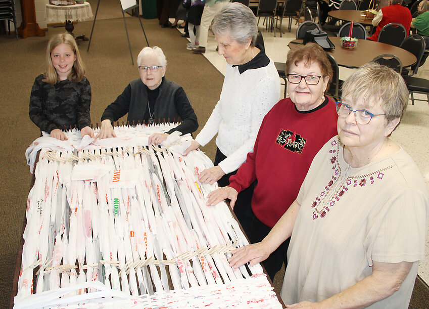 Volunteers weave protective mats for homeless people at Estherville UMC. From left, Angela Linn, Gladys Godfrey, Kathy Culbertson, Mona King, and Gerry Boe work together on a mat made from plastic bags.