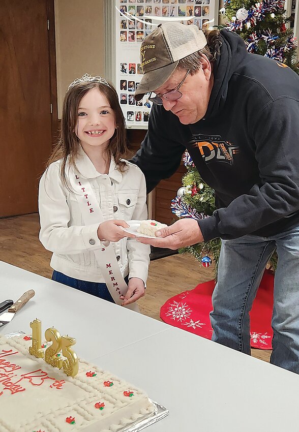 Ringsted Little Miss Mermaid Kinsley Lown hands the first piece of the town’s quasquicentennial cake to Mayor Mike Rasmussen during the town’s kickoff event this past Saturday.